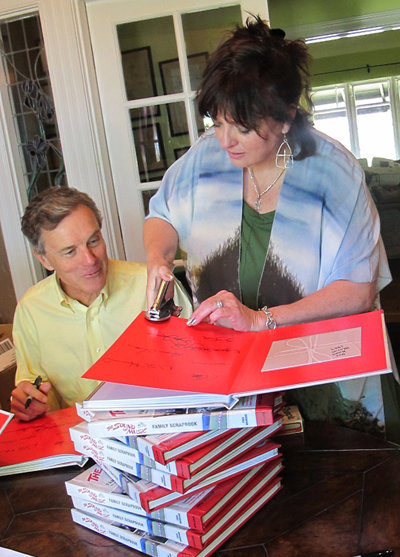 Angela embosses The Sound of Music Family Scrapbook with the official seal and signs the book with Nicholas